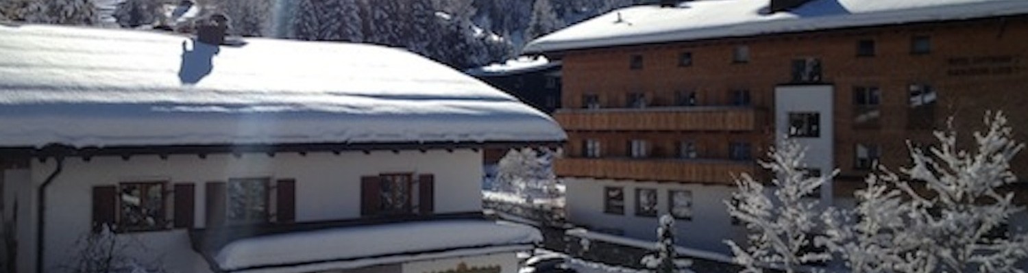 Häuser im Schnee, Sonnenschein und ein Berg im Hintergrund