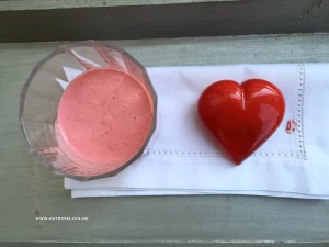 Ein Glas mit einem rosa Getränk und ein Herz